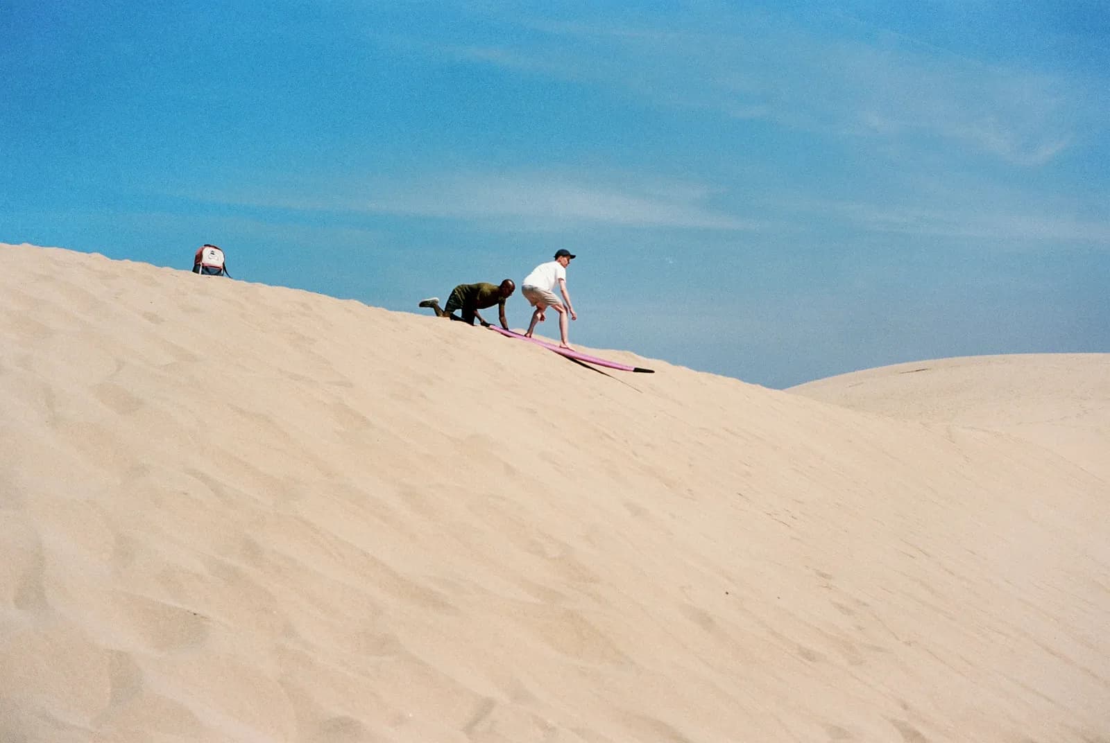 Sandboard à Essaouira : un rider descend une grande dune de sable sur sa planche, accompagné d'un guide, près de Sidi Kaouki — Windy Essaouira