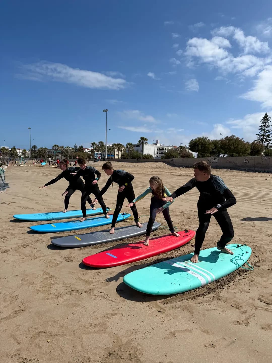 Cours de surf collectif à Essaouira — groupe d'élèves apprend le pop-up sur la plage