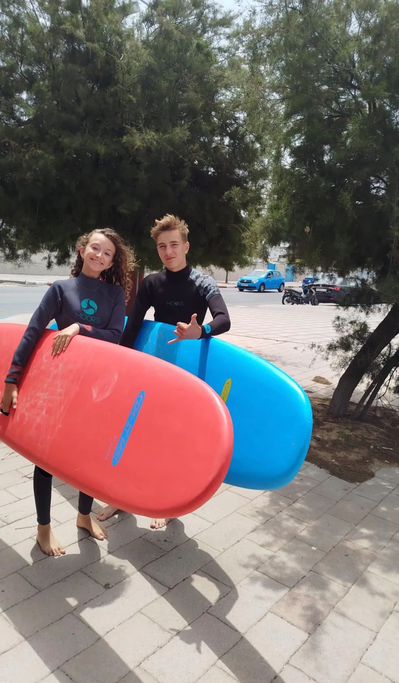 Deux adolescents en combinaison tenant leurs planches de surf en mousse avant un cours de surf enfants à Essaouira — Windy Essaouira