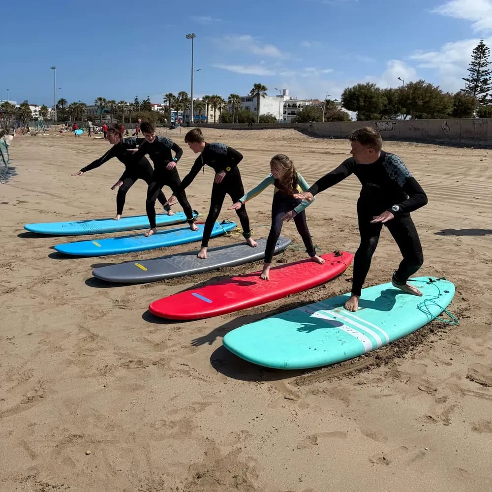 Groupe d'enfants et d'ados apprenant le pop-up sur la plage lors d'un cours de surf à Essaouira